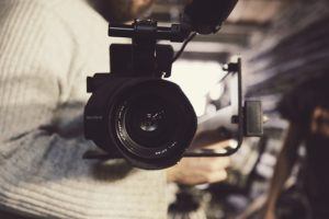 migliori editor video: telecamera e persona con maglione bianco