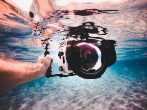 Mano sott’acqua che tiene una macchina fotografica subacquea